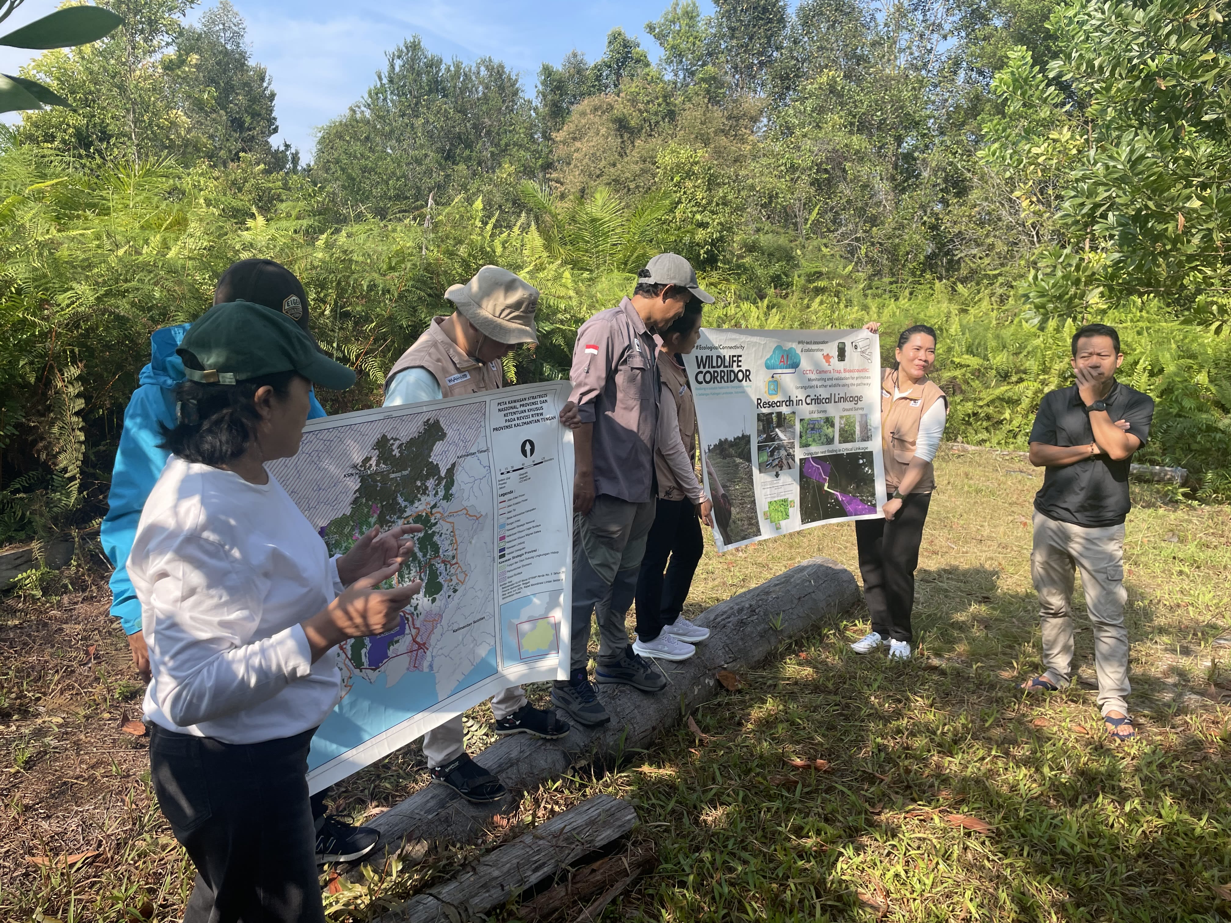 Several people holding up large maps and information on the creation of a wildlife corridor in Borneo.