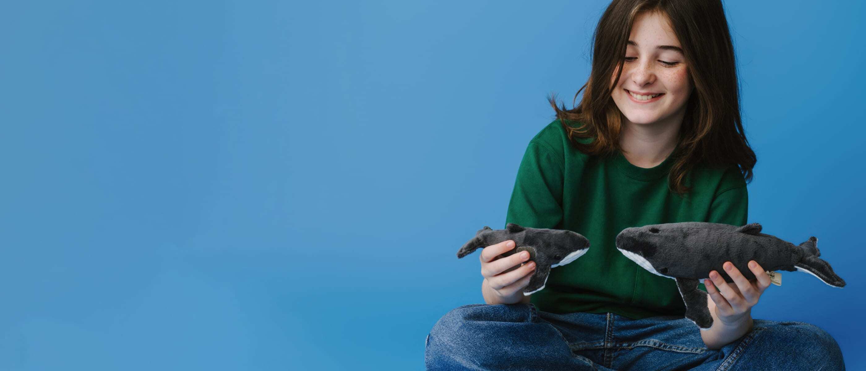A child plays with 2 whale soft plush tpys featuring a mother and baby whale from the WWF-Australia Adopt A Whale program.