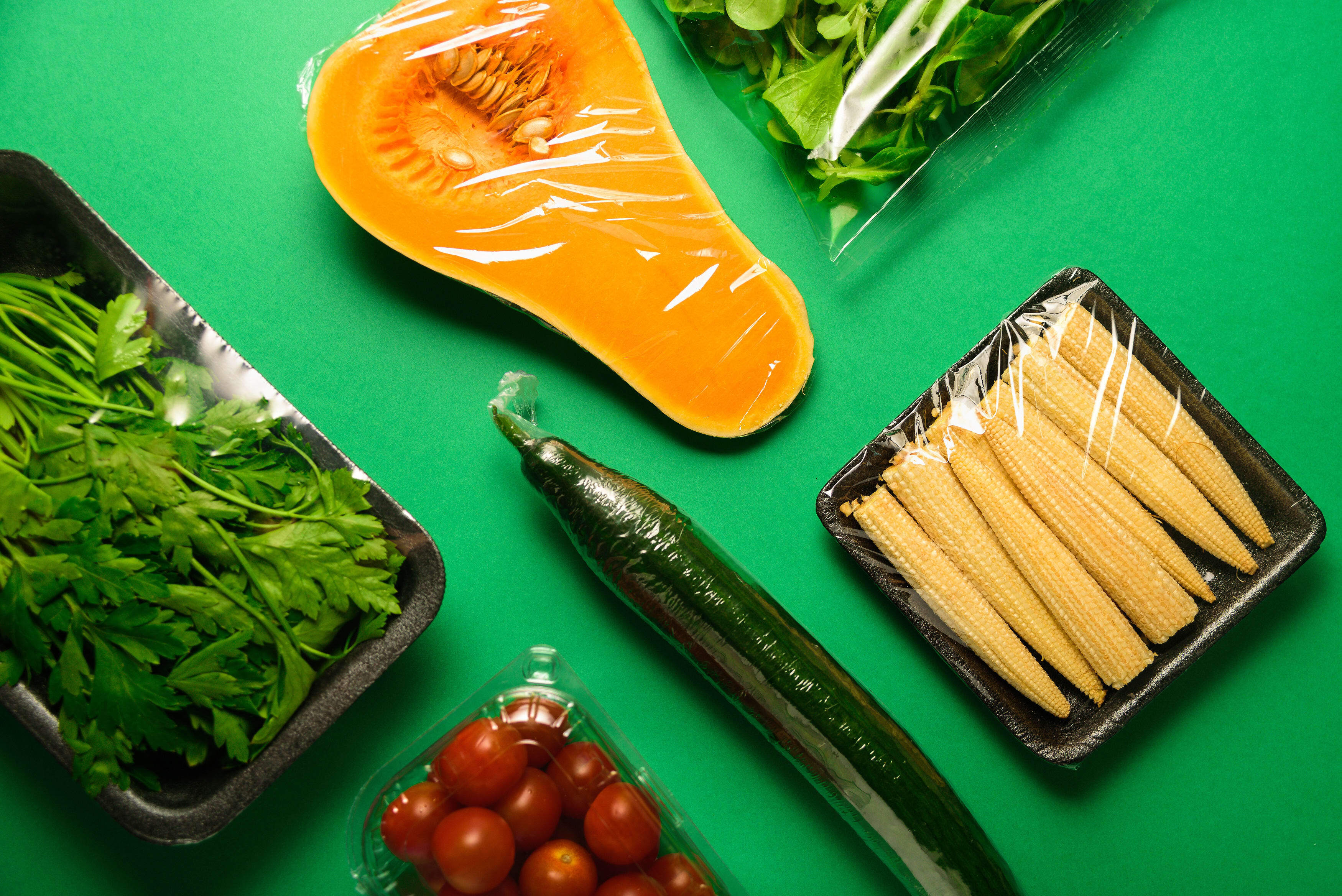 Fresh vegetables in plastic package. Zero waste, recycle concept. Plastic pollution. Green background