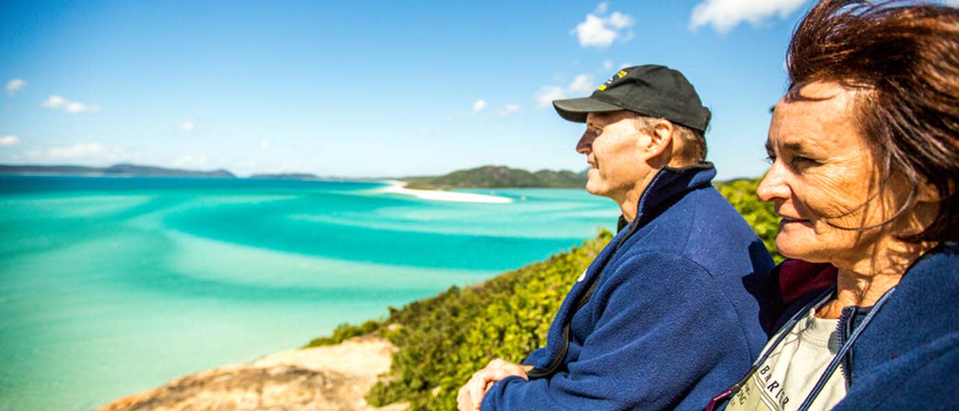 a man and a woman look out over Whitehaven beach
