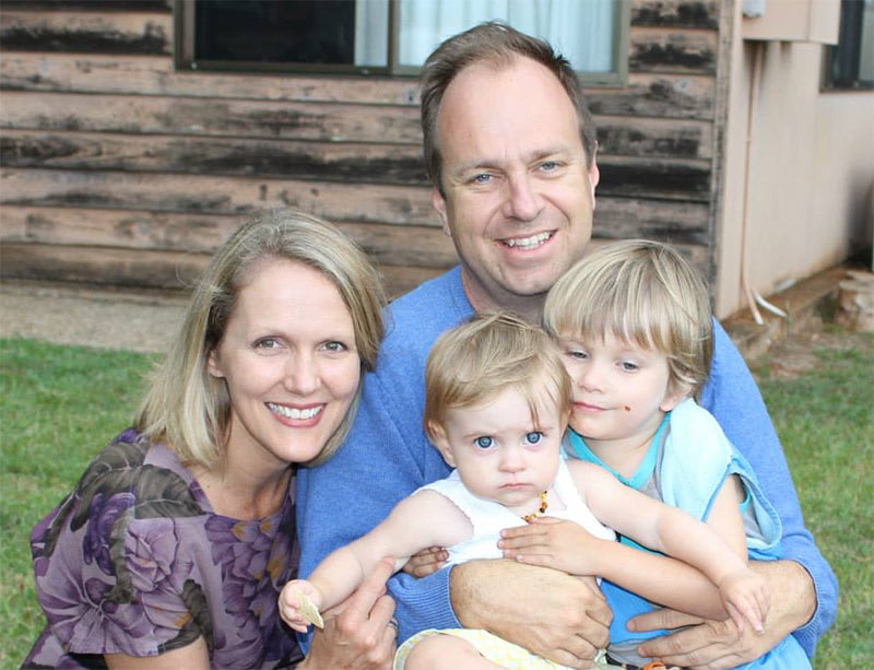 A family of a man, woman and two kids smile at the camera