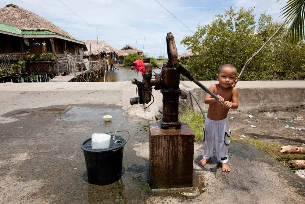 A little boy pumping out water for his bath in Donsol Sorsogon, Bicol, Philippines,&nbsp;May 2009