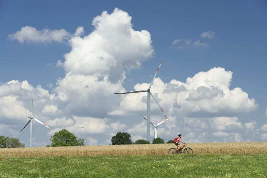img_woman_rides_past_wind_turbines_grassy_field_australia