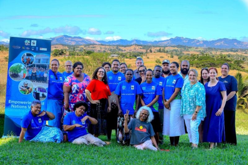 A group photo of people from WWF Pacific in a grass landscape with mountains in the background. © WWF-Pacific